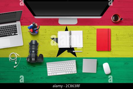 Ghana flag background with headphone,camera, notebook and mouse on national office desk table.Top view with copy space.Flat Lay. Stock Photo