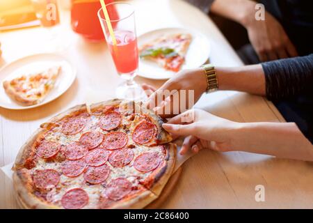 Selective focus of fresh just baked hot selfmade pizza with salami, tomato, cheese on wooden table background. Stock Photo