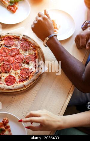People sharing delicious hand made pizza at home - Close up of hands taking pizza pepperoni slice - Fast food, Street food, Italian Food and Party, Fr Stock Photo