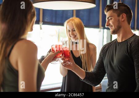 Happy multietnhic friends enjoying appetizer in american bar, cheering with tropical fruits cocktails, enjoying leisure time spending together. Stock Photo