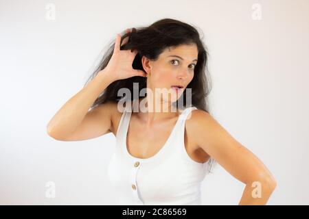 Pretty young woman with long black hair making listening gesture Stock Photo