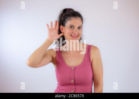 Pretty young woman with long black hair making listening gesture Stock Photo