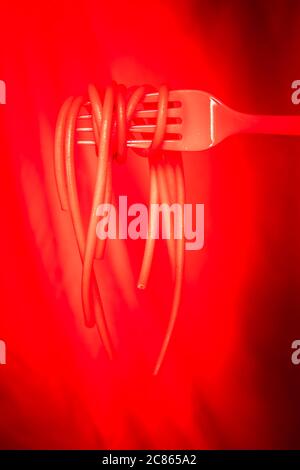 Spaghetti new defined. Hot red spaghetti on a red fork on black background Stock Photo