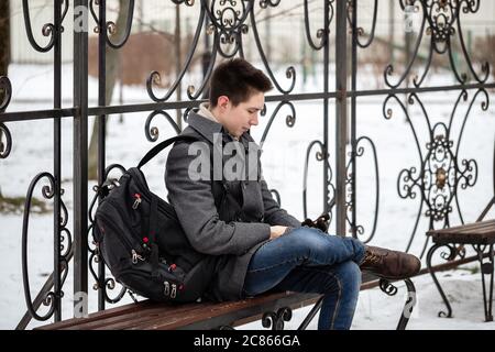 A young man is looking for information on his mobile phone. The guy is watching text messages on his smartphone in the city. Distance relationship con Stock Photo