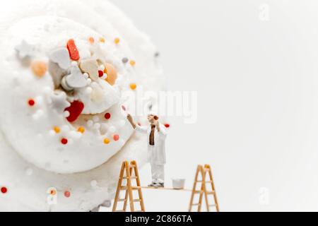 Miniature painter colouring giant cupcake Stock Photo