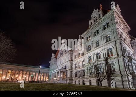 North entrance to granite and red roof New York State Capitol building at night with state Education Department building in the background. Stock Photo