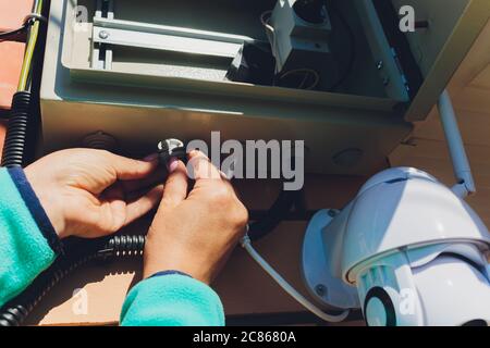 technician female setup cctv camera on wall. Stock Photo