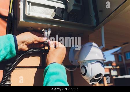 technician female setup cctv camera on wall. Stock Photo