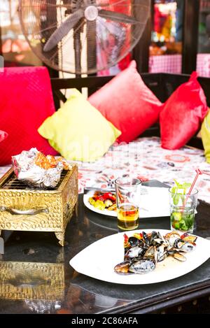 Seafood set with freshly fished crab, squid and shrimps prepared on a cooper barbecue on a wooden table in the restaurant. Healthy natural food. Stock Photo