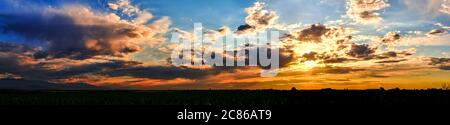 Bright sunlight shining through the clouds against the backdrop of a breathtaking evening sky at sunset. panorama, natural composition Stock Photo