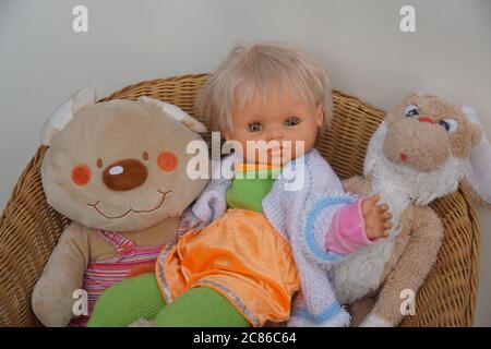 Plush, stuffed animal toy collection on a wicker chair with a white gray background. Includes a doll, teddy bear and a hare. Netherlands, January Stock Photo