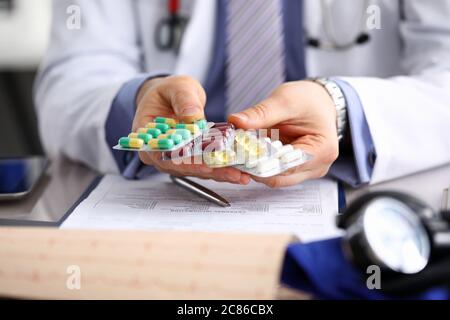 GP in clinic holding pack of different blisters Stock Photo