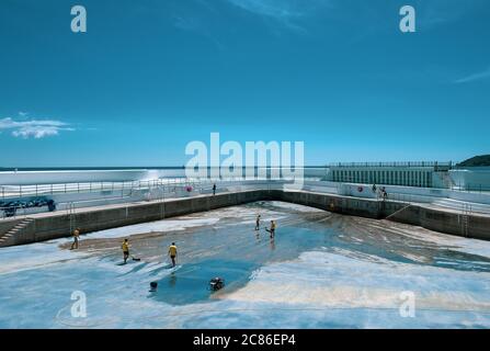 Lifeguards cleaning algae of the bottom of Jubilee Pool, Penzance; pre re-filling and re-opening on 25th July 2020 after the coronavirus lockdown. Stock Photo