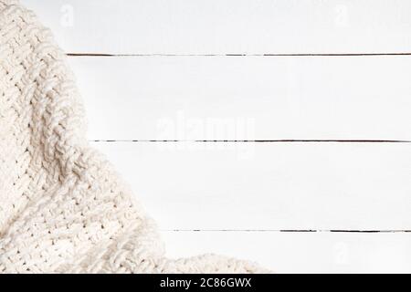 Warm light beige wool fabric on a white wooden background with copy space. Cozy and soft winter background Stock Photo