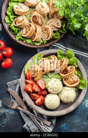 Pork rolls stuffed with mozzarella and sun-dried tomatoes served with mashed potatoes and salad Stock Photo