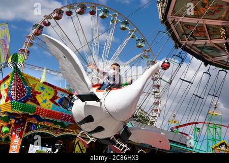 Dortmund, Germany, July 21, 2020: Girl riding a swan. The temporary pop-up amusement park 'funDOmio' was opened on June 25, 2020 at the exhibition center around Dortmund's Westfalenhalle. The showmen want to compensate a little for the bitter losses caused by the corona-related closings of the fairs. The amusement park is open until August 11th, 2020. Stock Photo