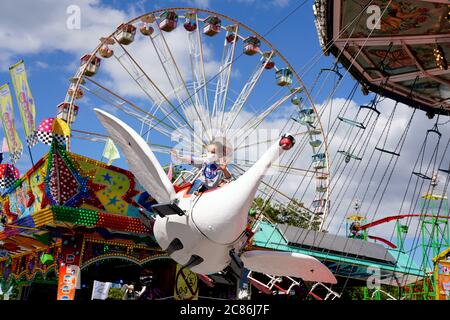 Dortmund, Germany, July 21, 2020: Girl riding a swan. The temporary pop-up amusement park 'funDOmio' was opened on June 25, 2020 at the exhibition center around Dortmund's Westfalenhalle. The showmen want to compensate a little for the bitter losses caused by the corona-related closings of the fairs. The amusement park is open until August 11th, 2020. Stock Photo