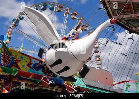 Dortmund, Germany, July 21, 2020: Girl riding a swan. The temporary pop-up amusement park 'funDOmio' was opened on June 25, 2020 at the exhibition center around Dortmund's Westfalenhalle. The showmen want to compensate a little for the bitter losses caused by the corona-related closings of the fairs. The amusement park is open until August 11th, 2020. Stock Photo