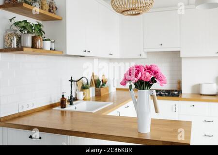 Peony flowers in vase on clean white kitchen in modern style, kitchen details. Sustainable living eco friendly kitchen Stock Photo