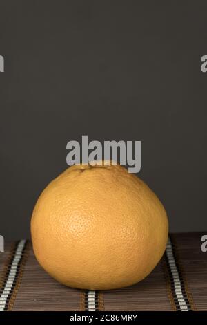 On a black mirror background One grapefruit on a bamboo brown background Stock Photo