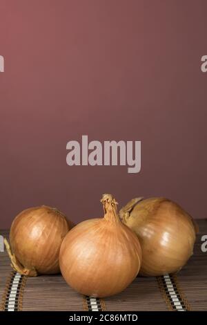Three onions on board cutting, red background Stock Photo