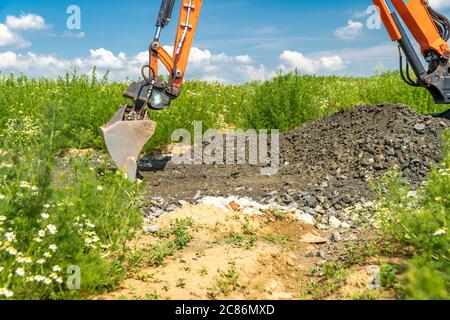 An excavator metal bucket digs sand or clay on a construction site ...