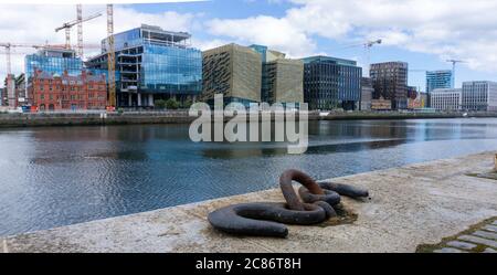 A ships mooring  ring on Sir John Rogersons Quay in Dublin set against the modern office developments on the North Wall Quay of the River Liffey. Stock Photo