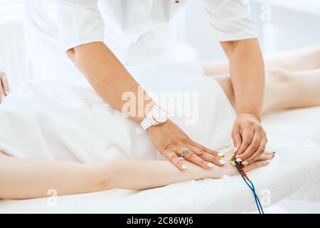 Close-up of a beautician s hand giving electrodes therapy on young woman's hand in clinic.