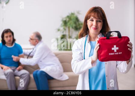 Two doctors visiting sick man at home Stock Photo