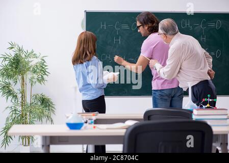 Old teacher and two students in the classroom Stock Photo