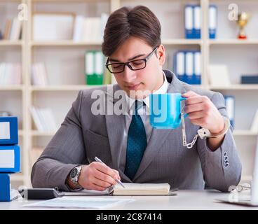 The businessman chained with handcuffs to his coffee Stock Photo