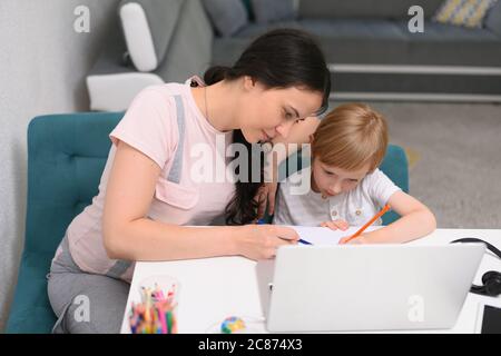 Online courses for preschoolers. 5 years boy uses a laptop at home. Homework with his mother in quarantine at home during covid 19 coronavirus pandemi Stock Photo
