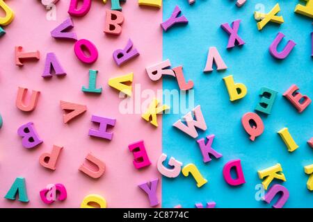 A set of letters for studying the alphabet. Multicolored wooden letters on a blue and pink background. Education, back to school concept. Stock Photo