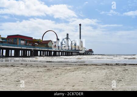 Looking across the beach and sand towards Galveston Island Historic Pleasure Pier in the Gulf Of Mexico, Texas. Stock Photo