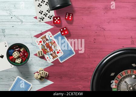 Bahrain casino theme. Aces in poker game, cards and chips on red table with national wooden flag background. Gambling and betting. Stock Photo