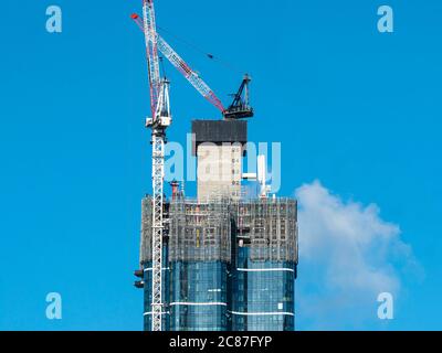 Construction site of modern multi-level building with a clear blue sky. Workers operating machinery. Stock Photo