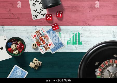 Iraq casino theme. Aces in poker game, cards and chips on red table with national wooden flag background. Gambling and betting. Stock Photo