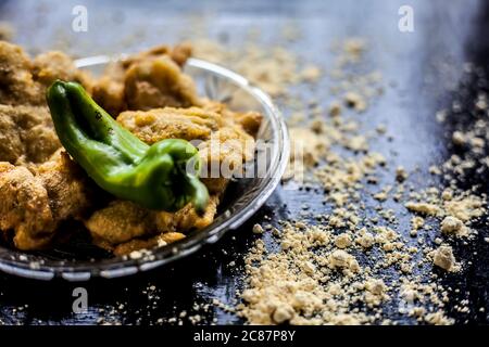 Famous Aloo pakora/ aloo bhajia in a glass plate with green chili and some chickpea flour spread on a surface.Shot of alu bhajiya on a transparent gla Stock Photo