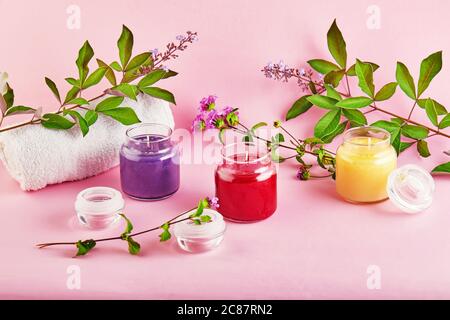 Scented candles for Spa and home with green leaves on a pink background. Stock Photo