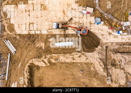 excavator moving ground and loading into a dumper truck on construction site. top down view of city building site. Stock Photo