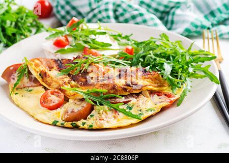 Omelette with tomatoes, cheese and green herbs on plate.  Frittata - italian omelet. Stock Photo