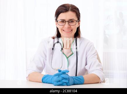 Female physician in glasses sitting in her bright cabinet Stock Photo
