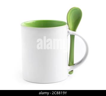White cup mug with green inside and orange ceramic spoon standing on white background, isolated Stock Photo