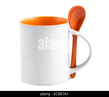 White cup mug with orange inside and orange ceramic spoon standing on white background, isolated Stock Photo