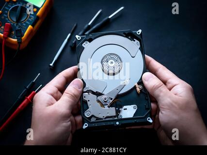 Man hands with screwdrivers and digital mutimeter fixing hard drive Stock Photo