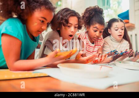 Surprised children painting with their hands during the art class Stock Photo