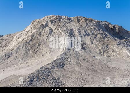 sunny illuminated dry spoil pile in front of blue sky Stock Photo