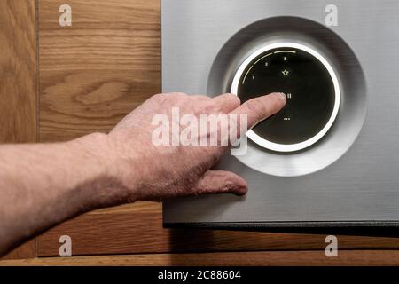 User using the OLED touch panel on a high end smart speaker, getting reading to start playback of a download music stream. Stock Photo