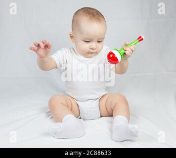 Picture of a eight month old baby with rattle in mouth Stock Photo