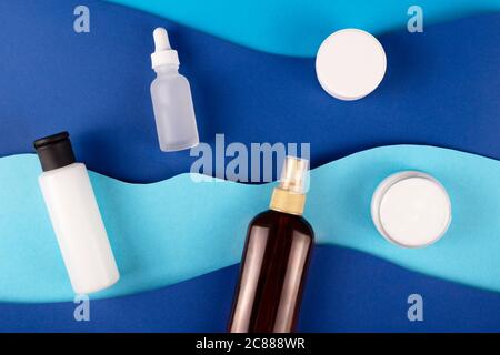 Blue paper art sea waves with sunscreen. Travel skin care products. Stock Photo